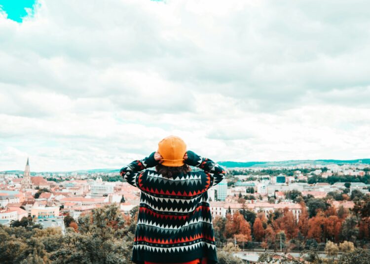 person in black and red plaid dress shirt standing on rock formation during daytime