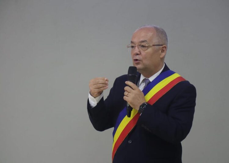 A Romanian Football figure, Emil Boc, in a suit and tie speaking into a microphone amidst controversy.
