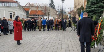 A woman in a red coat is standing in front of a group of Anti-Communist Political Prisoners.
