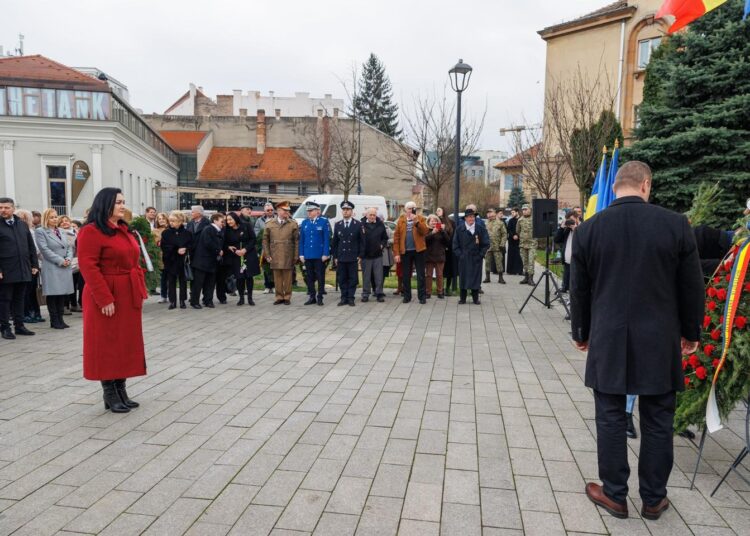 A woman in a red coat is standing in front of a group of Anti-Communist Political Prisoners.