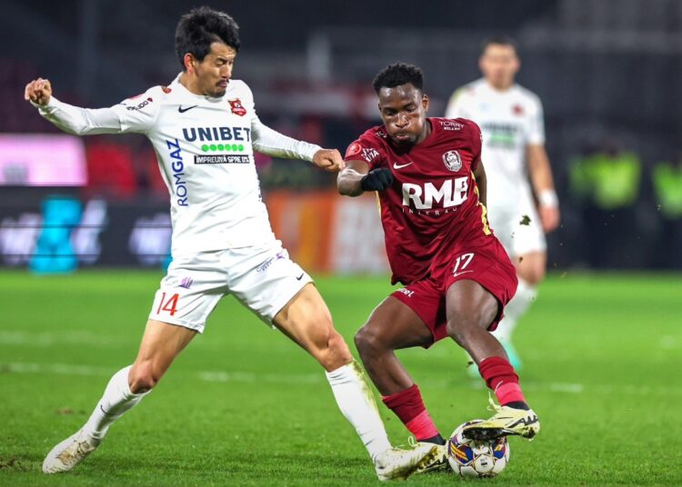 Two soccer players from CFR Cluj fighting for the ball on a soccer field during the regular season.