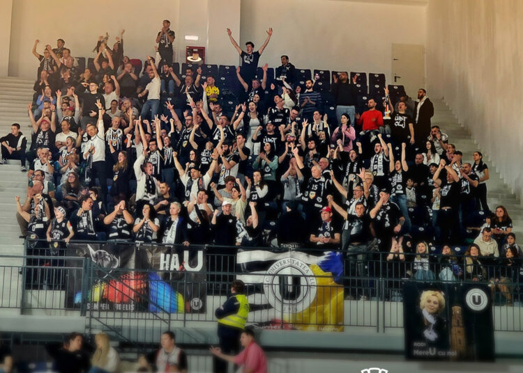 A group of people in bleachers at a CSM Oradea vs. U-BT Cluj-Napoca game.