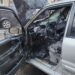 A burned-out car with the door open on Năsăud Street.